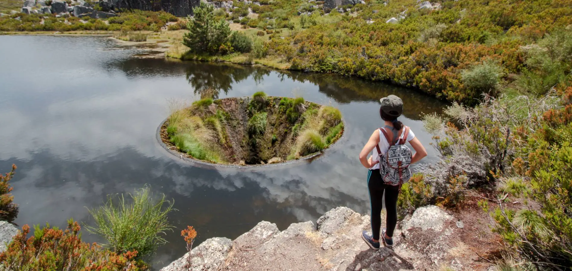 Caminhante junto a uma lagoa de montanha na Serra da Estrela
